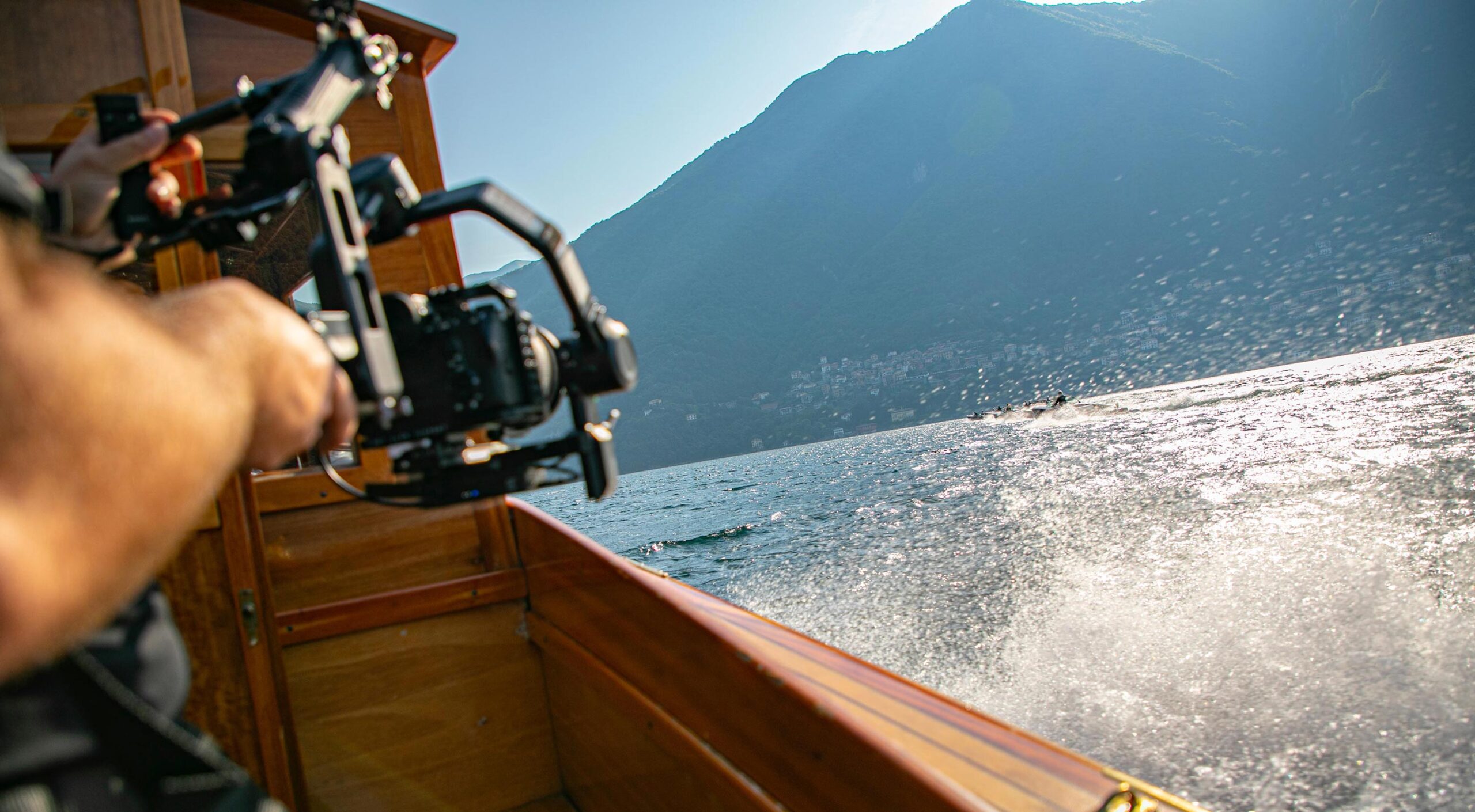 Sony A7S III camera on set during Como Classic Boats filming on Lake Como, Italy — cinematic water spray and historic wooden boats racing in background