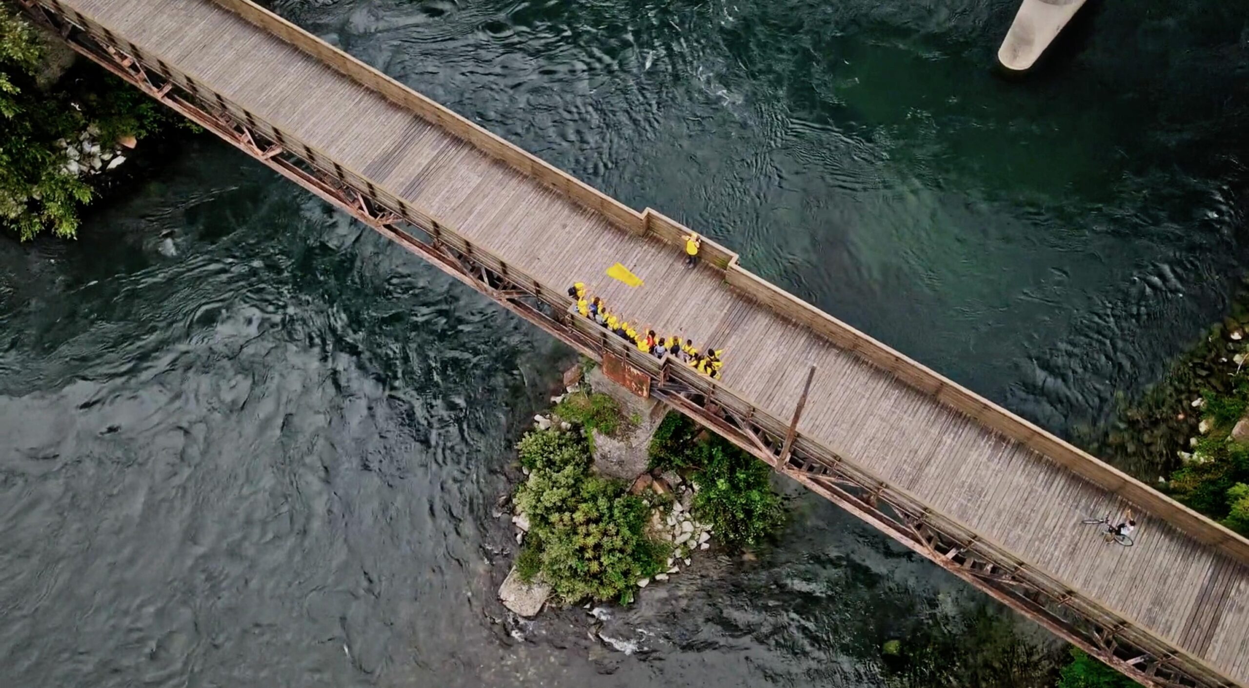 Aerial drone shot of visually impaired teenagers crossing wooden bridge over flooded river on Cammino di Leonardo — Noisy Vision documentary by Uptelling, Lecco to Milan inclusive walk 2021